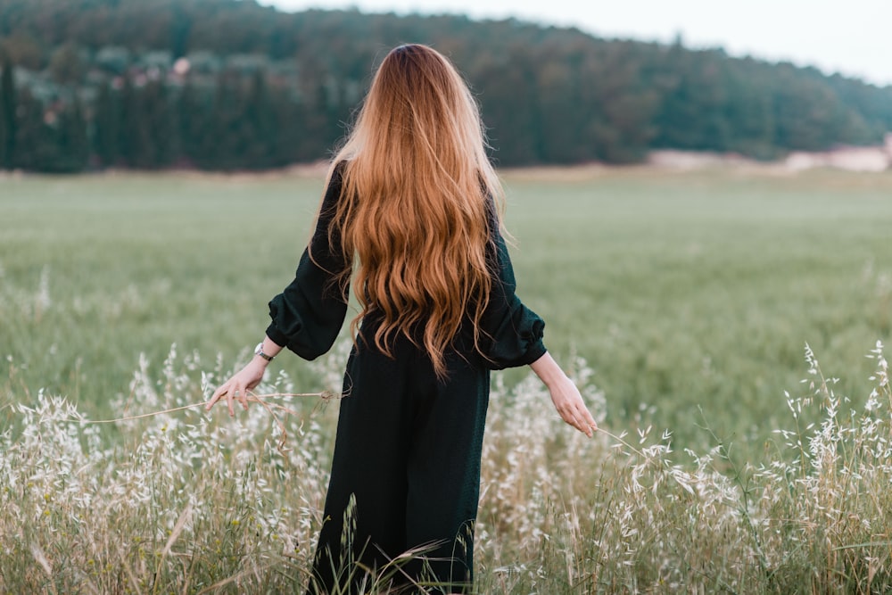 femme debout sur le champ d’herbe verte pendant la journée