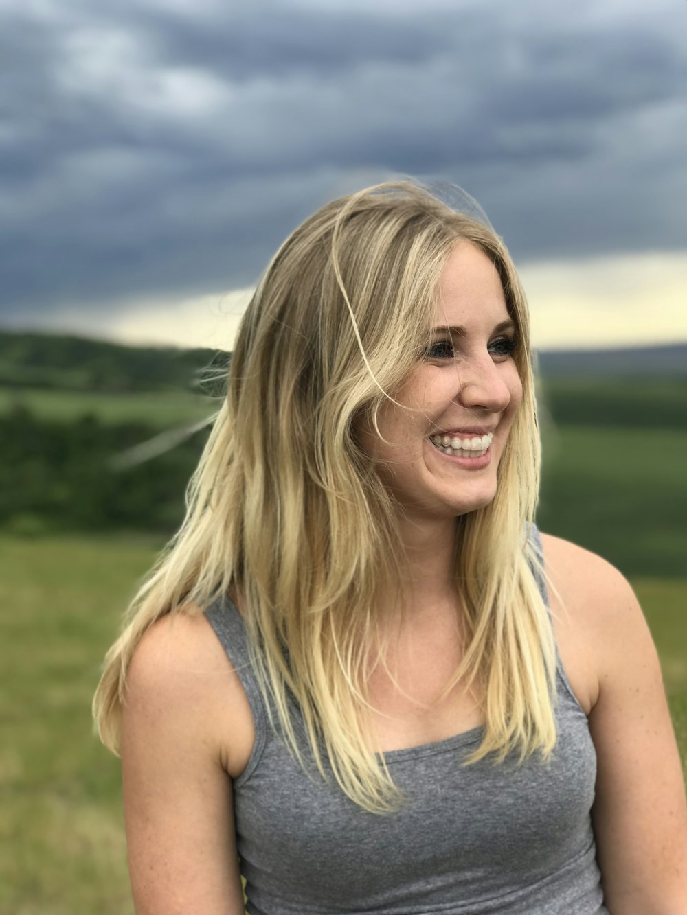 woman standing on open field while smiling selective focus photography