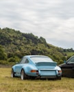 blue and black cars parked on green grass under white cloudy sky