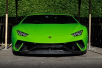 green Lamborghini Huracan sports coupe parked near wooden post