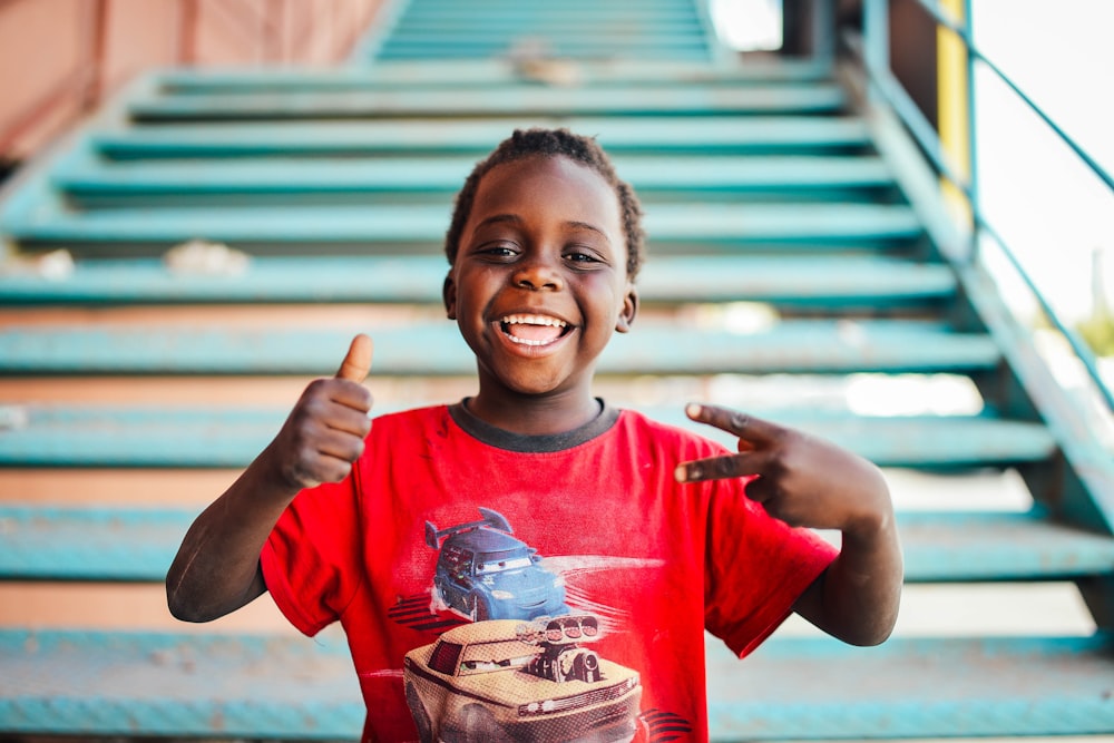 boy standing near stairs doing peace sign at daytime