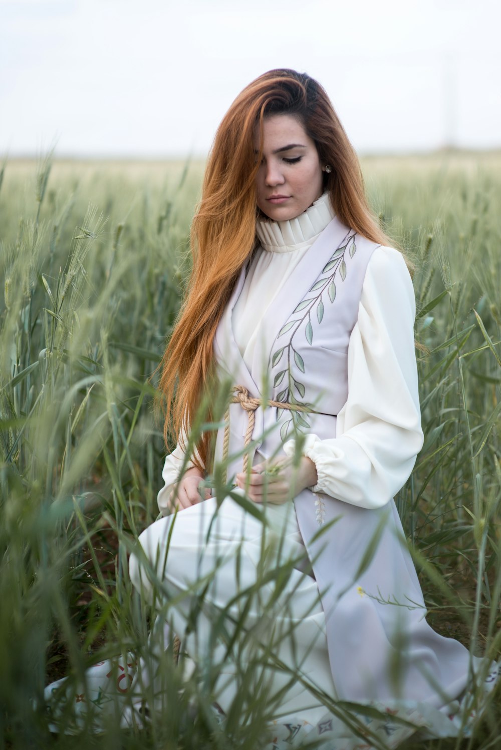 mulher no vestido branco segurando a grama verde durante o dia