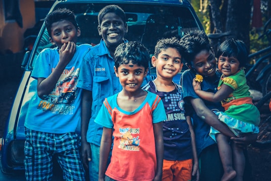 Smiling diverse group of international students and workers standing beside a reliable rental car in Brisbane.