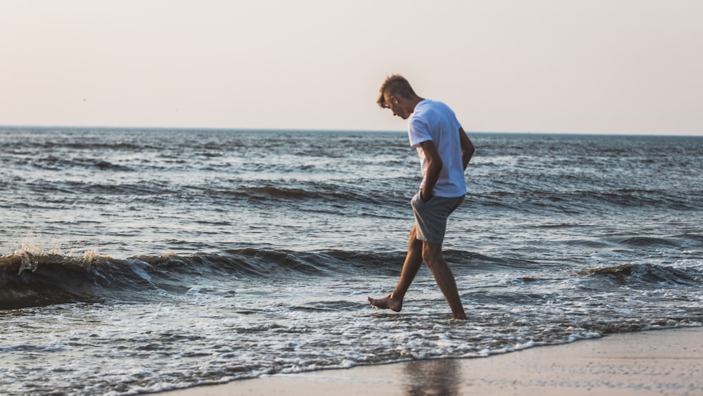 a man walking along a beach next to the ocean