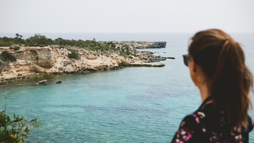 woman wearing black and pink top near cliff at daytime