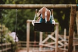 woman riding swing near trees