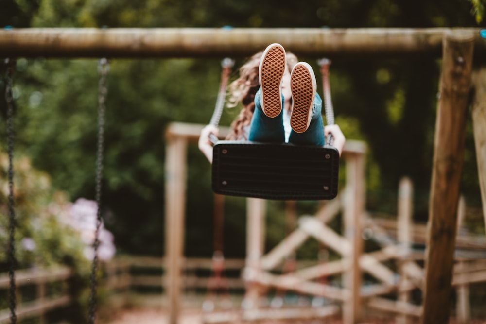 woman riding swing near trees