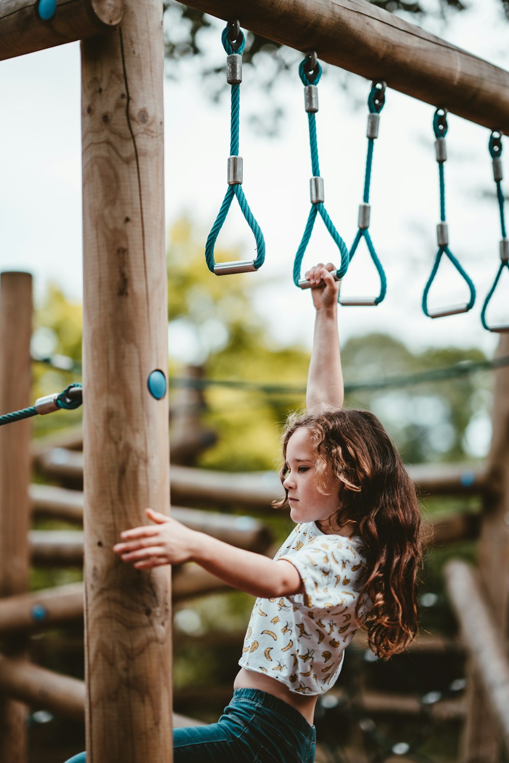 girl playing at monkey bar during daytime