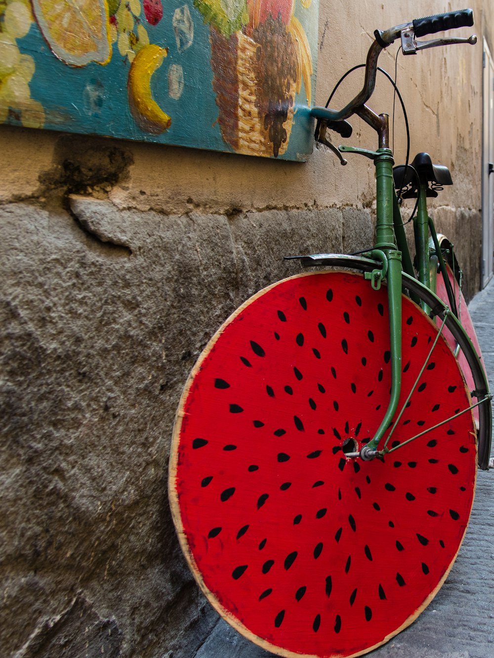 Bicicleta verde y roja estacionada junto a un muro de concreto