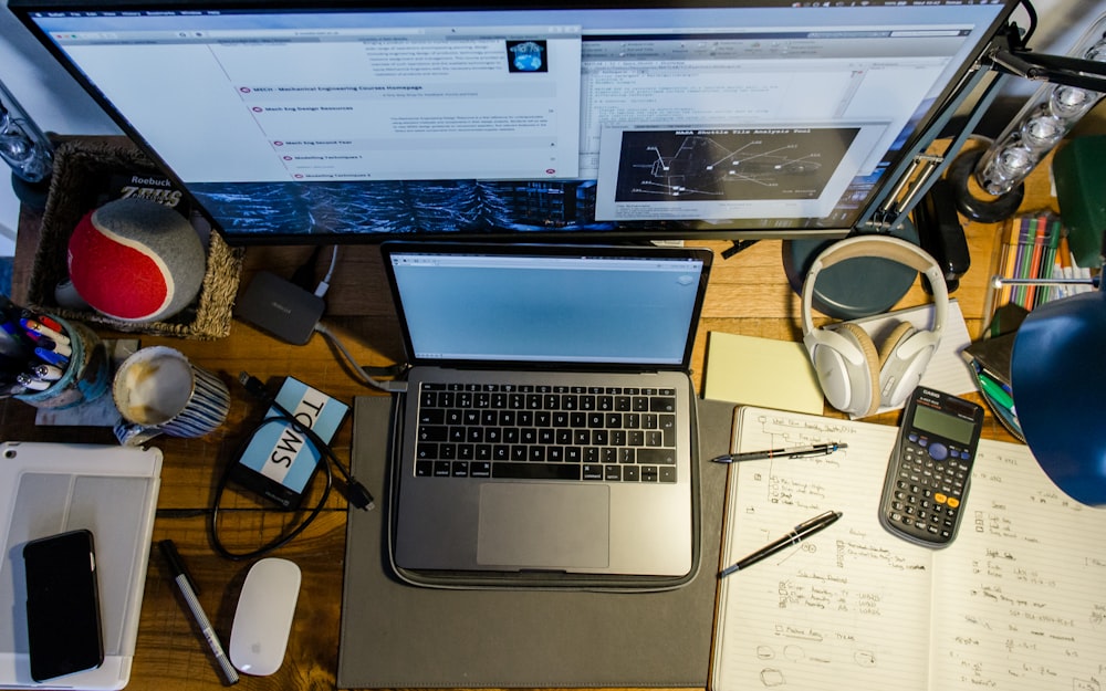Fotografía de ángulo alto de la computadora portátil cerca de la calculadora, los bolígrafos y el mouse