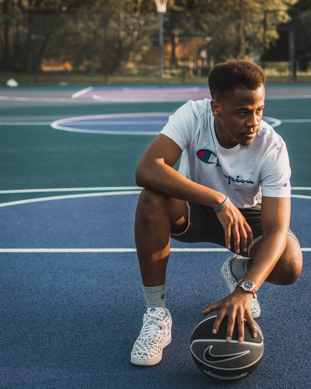 man leaning down picking-up basketball during daytime