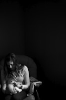 grayscale photo of woman holding a baby on her right hand while her left hand touching baby's face