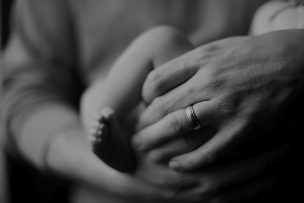 grayscale photo of person holding baby