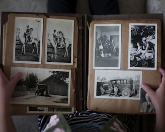 person opening photo album displaying grayscale photos