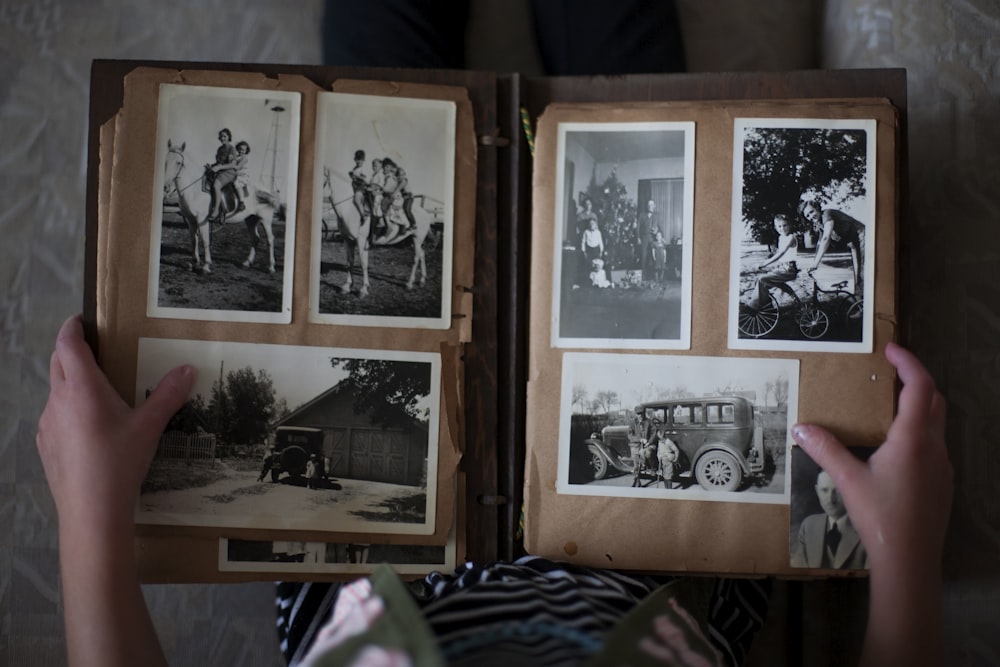 Pessoa abrindo álbum de fotos exibindo fotos em tons de cinza