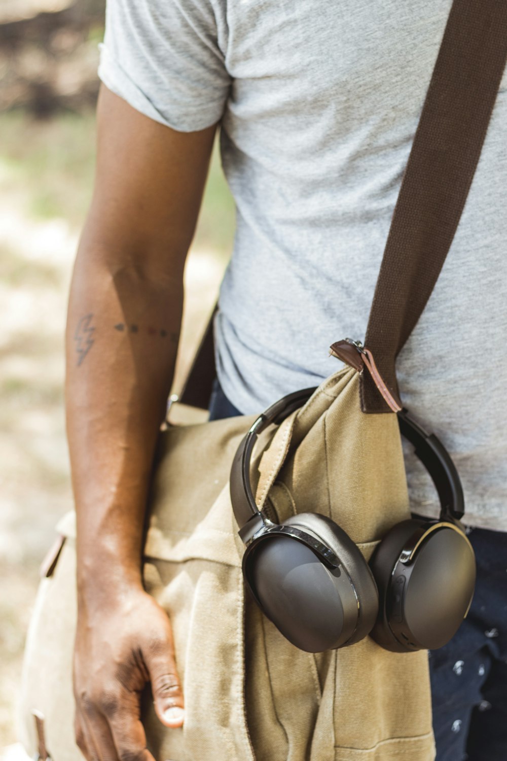man wearing brown crossbody bag with headphones hanged
