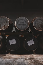 Copper stills gleaming in a rustic distillery setting with wooden barrels in the background.