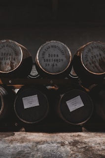 A dark, aged rum bottle resting on wooden barrels under warm lighting.