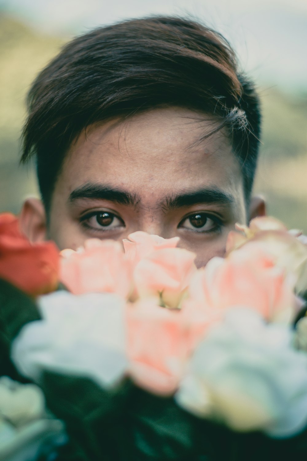 Hombre escondido detrás de flores rosas y blancas