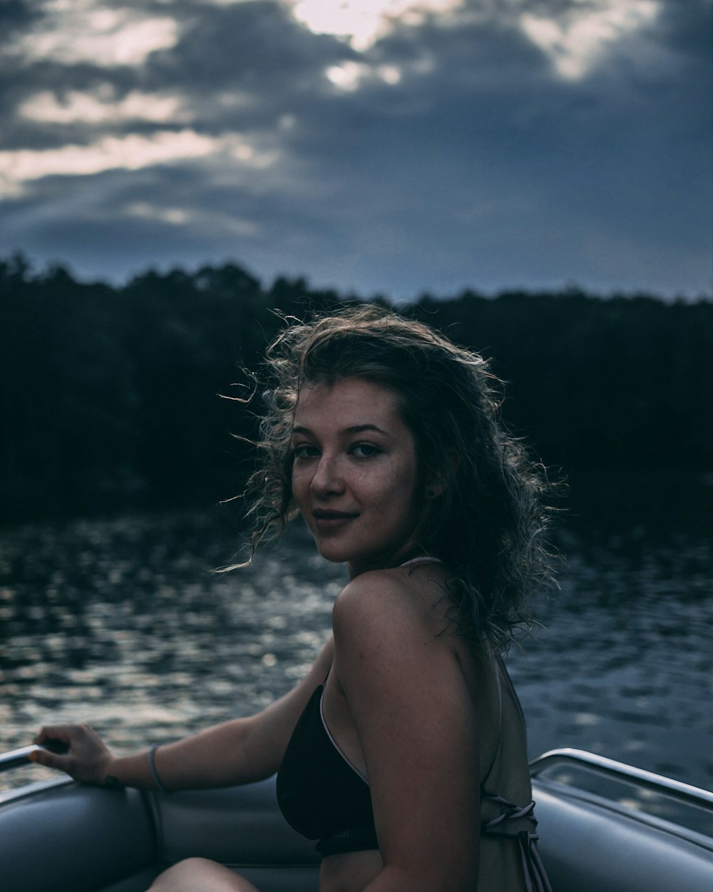 woman sitting on gray inflatable boat above body of water