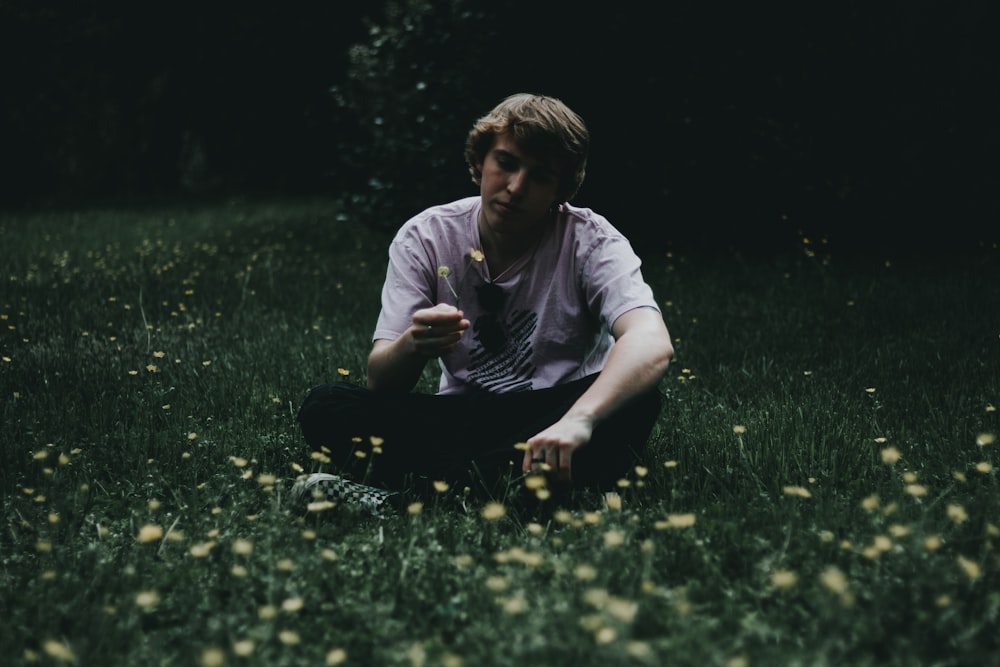 푸른 잔디밭에 앉아 꽃을 들고 있는 남자