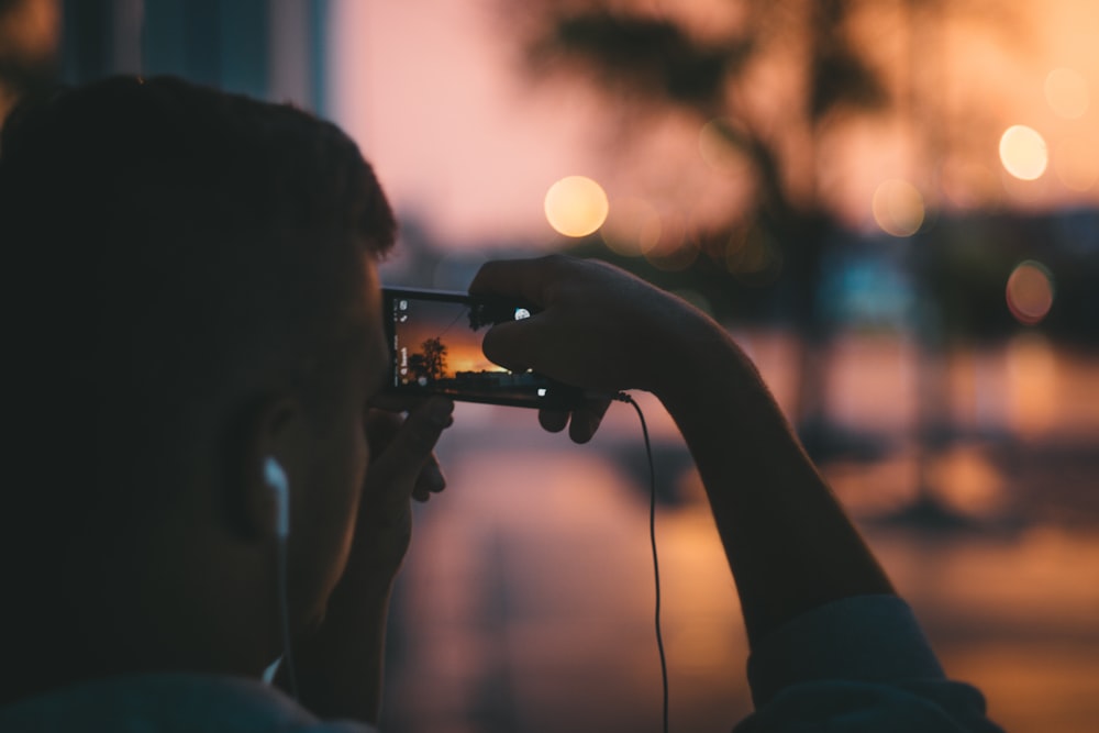 silhouette photo of man taking photo on palm trees