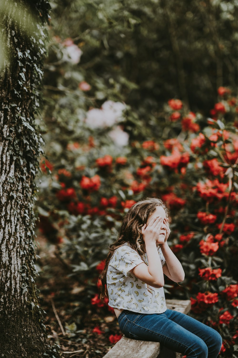 꽃 근처 나무 벤치에 앉아있는 소녀