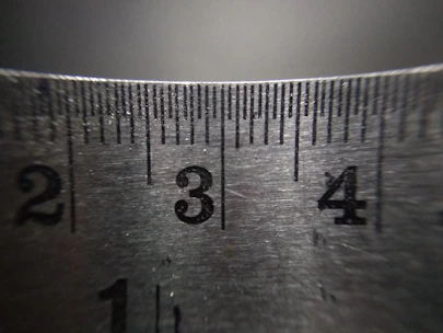 A hand holding a ruler over a printed photo to measure its size precisely.