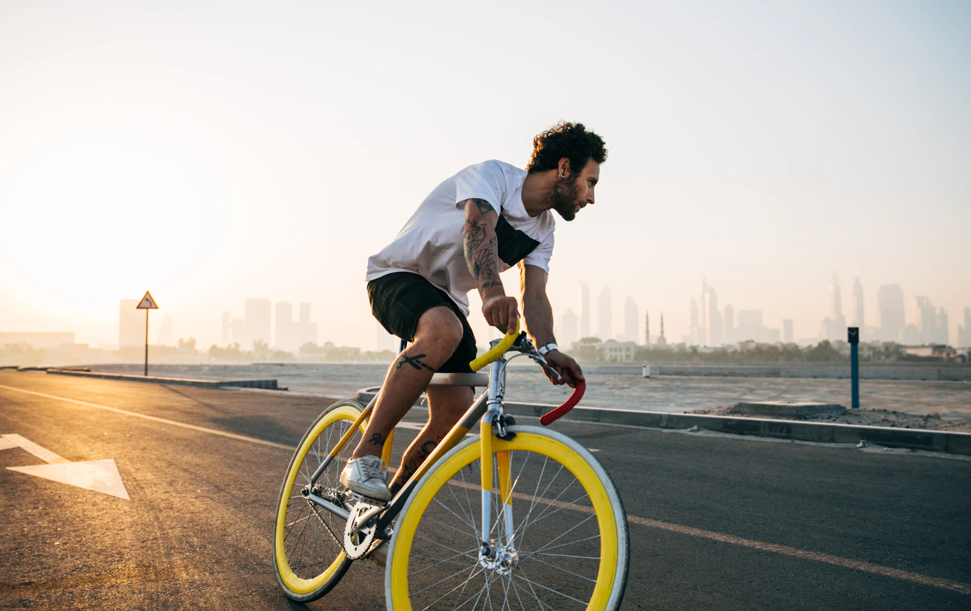 Ciclista a pedalar numa cidade com skyline ao fundo — mobilidade urbana