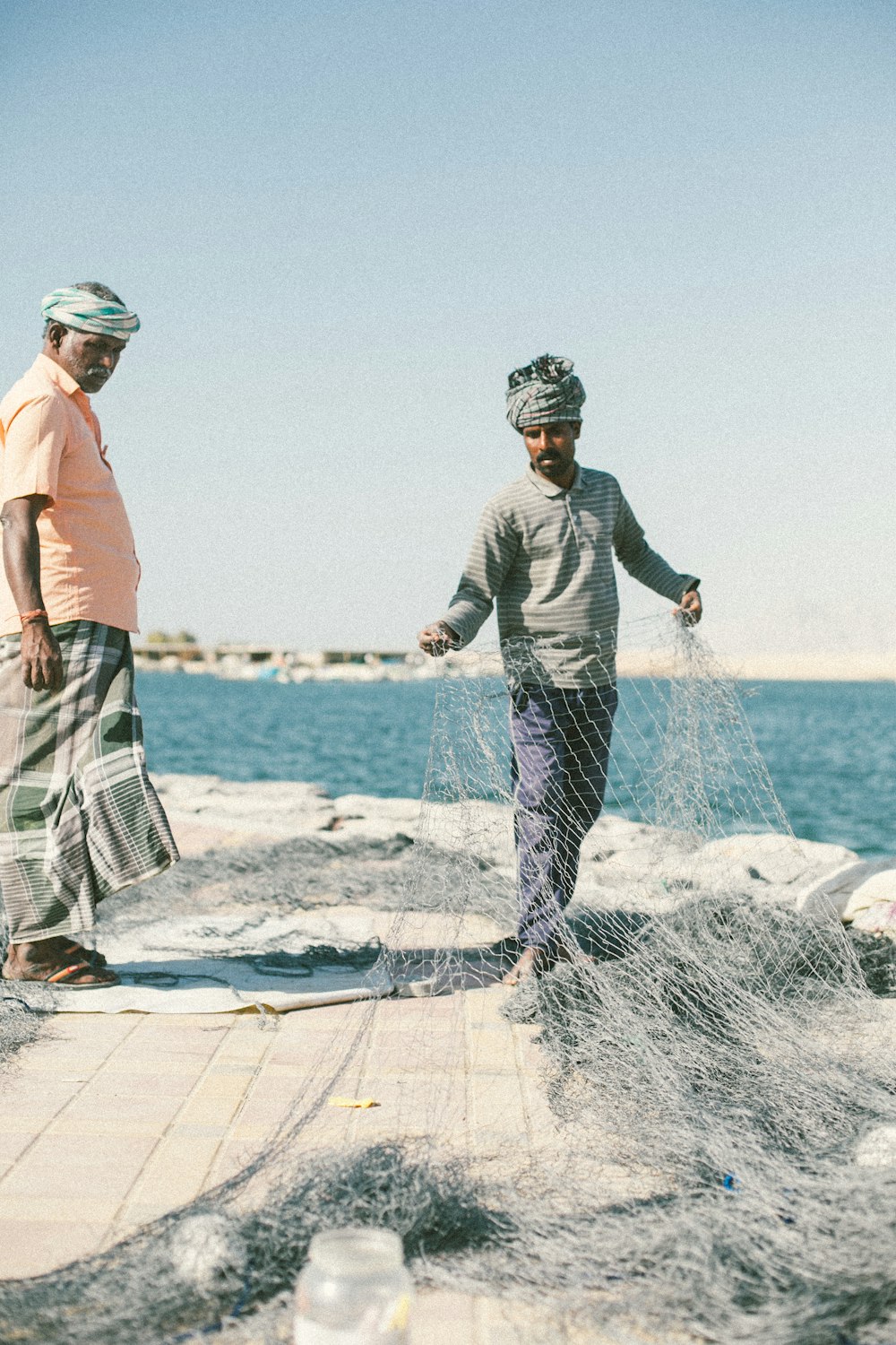 uomo che tiene la rete da pesca vicino al mare