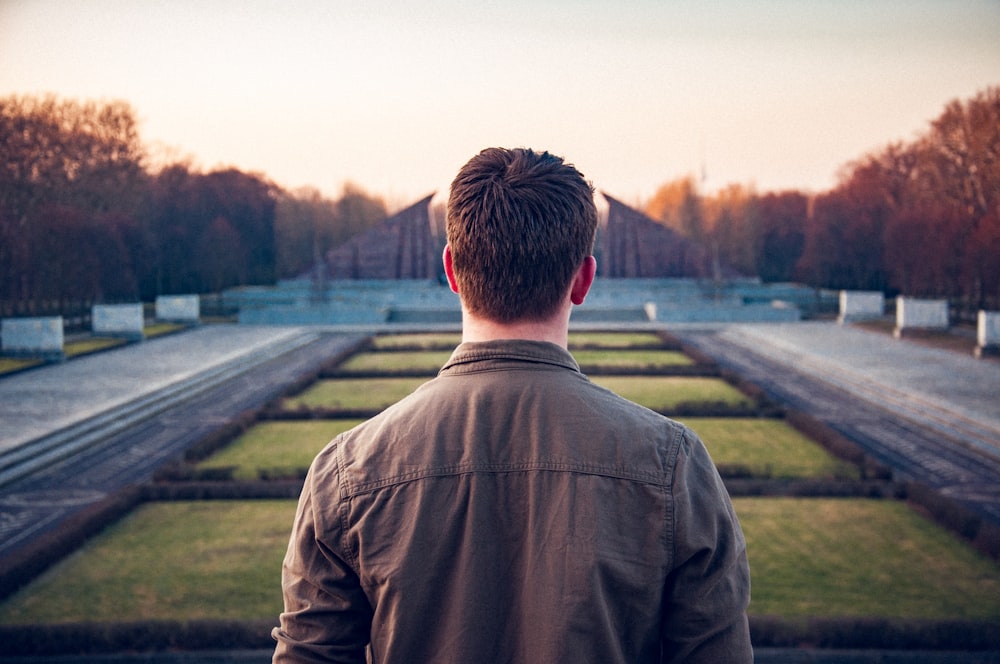 man standing between pathway during daytime