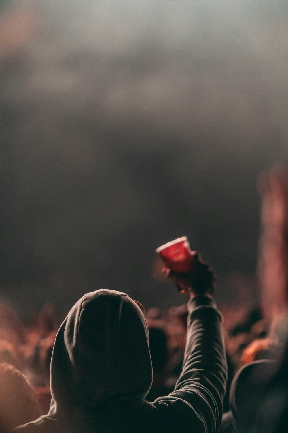 persona che alza la tazza sulla fotografia di messa a fuoco selettiva della folla