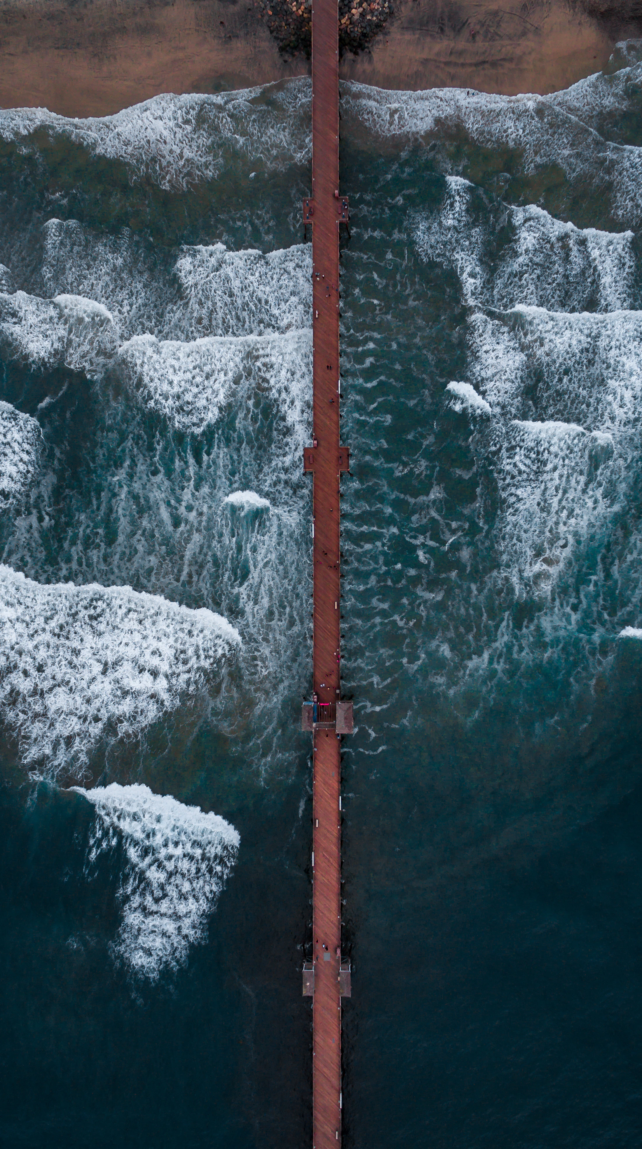 Aerial view of a pier walkway reaching out over the ocean