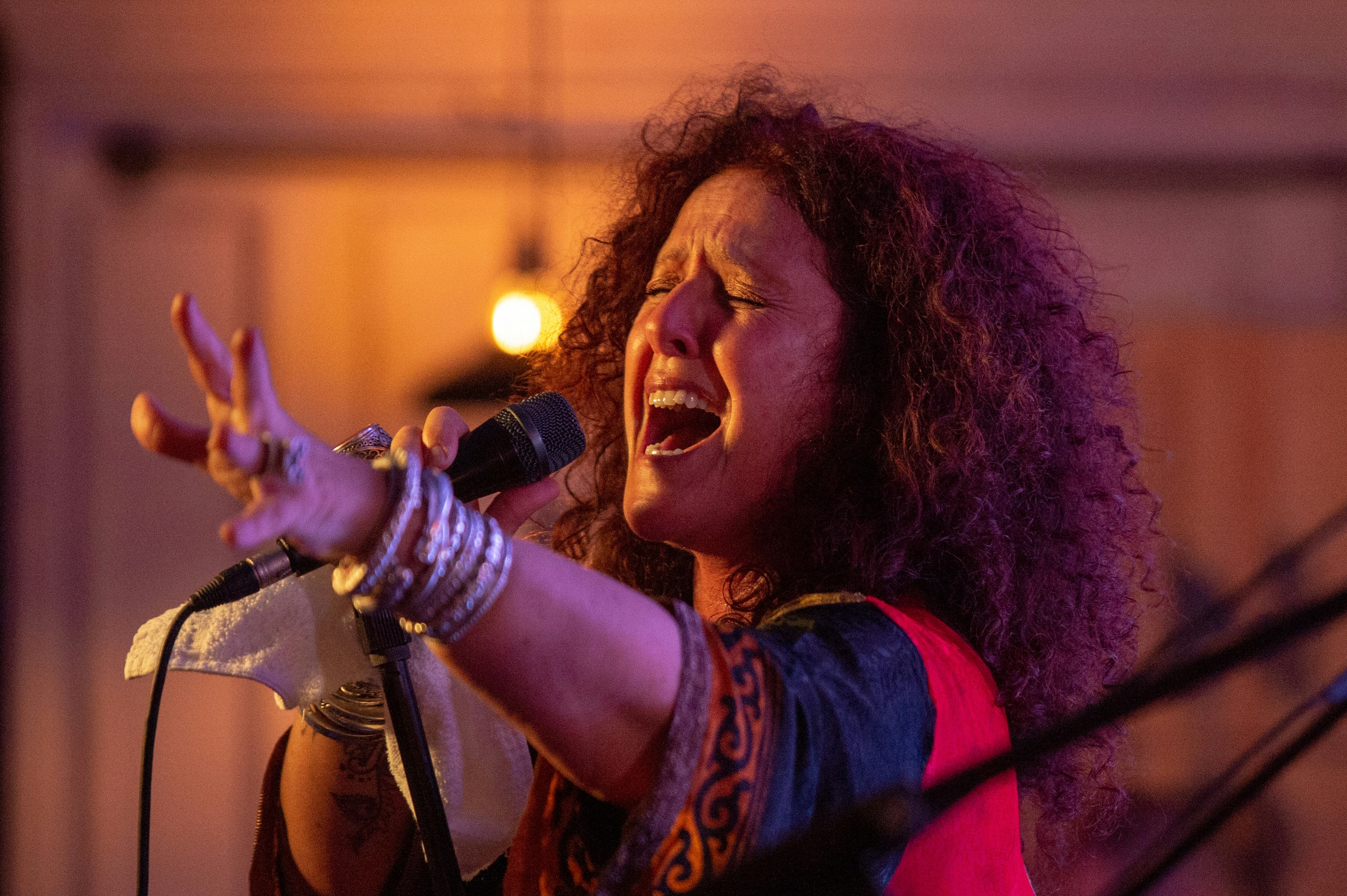 Female singer close-up performing with microphone, warm stage lighting, passionate expression