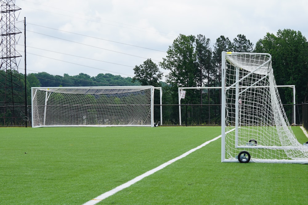 three white goal nets on grass field