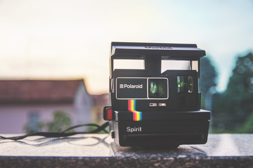 câmera terrestre Polaroid Spirit preta em surfac cinza e