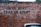 A brick wall has the phrase 'UNTIL DEBT TEAR US APART' spray-painted in black. A section of a parked car is visible at the bottom of the image, adding a touch of urban life.