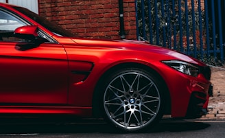 red BMW vehicle parked at the road near the blue gate