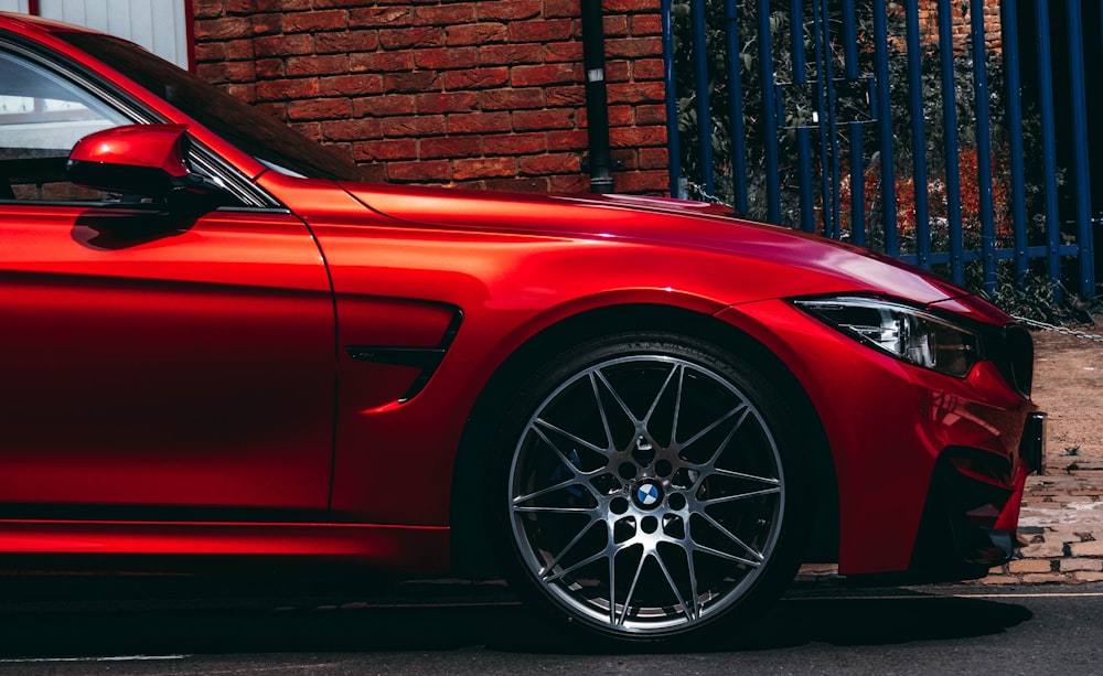 red BMW vehicle parked at the road near the blue gate