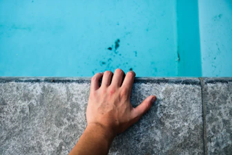 person's left hand holding gray concrete surface