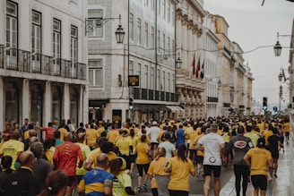 crowd of people running on the street near buildings during daytime