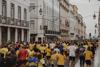 crowd of people running on the street near buildings during daytime
