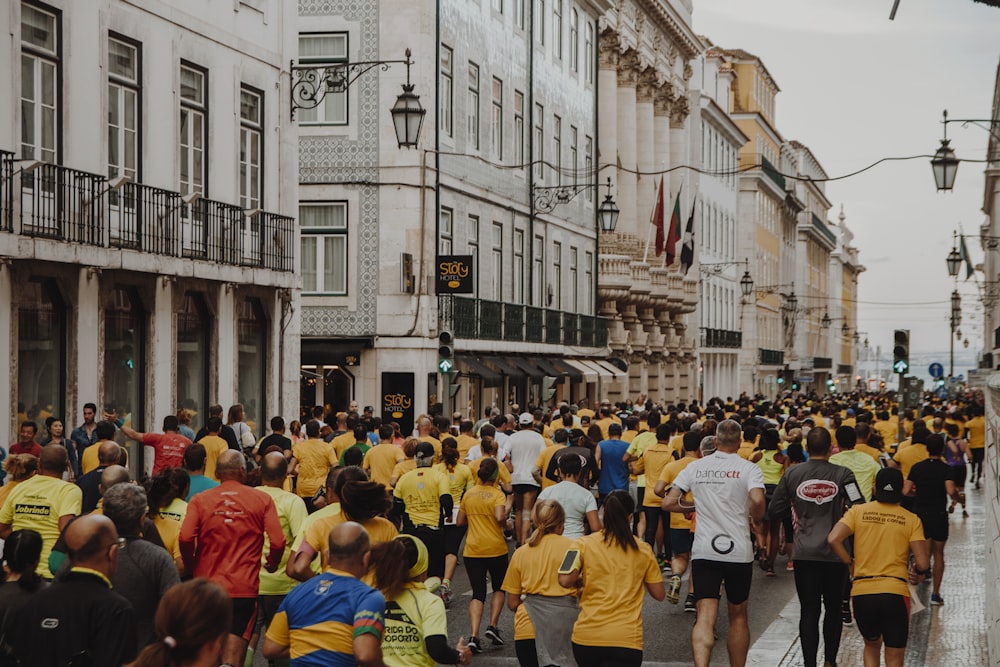 crowd of people running on the street near buildings during daytime