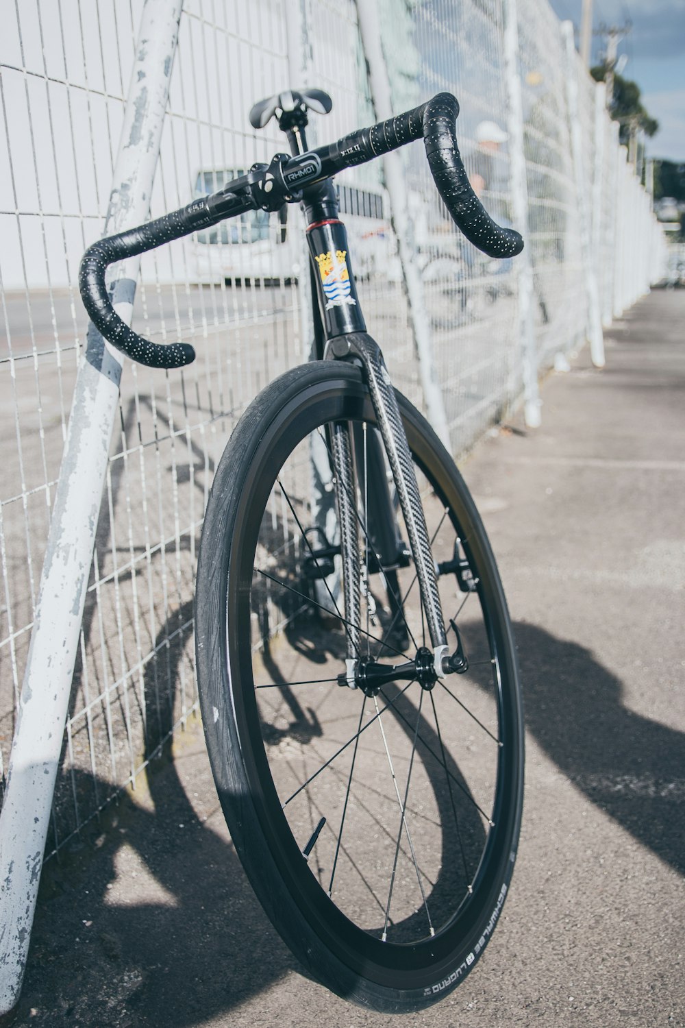 Bicicleta de carretera blanca y negra estacionada junto a la valla metálica