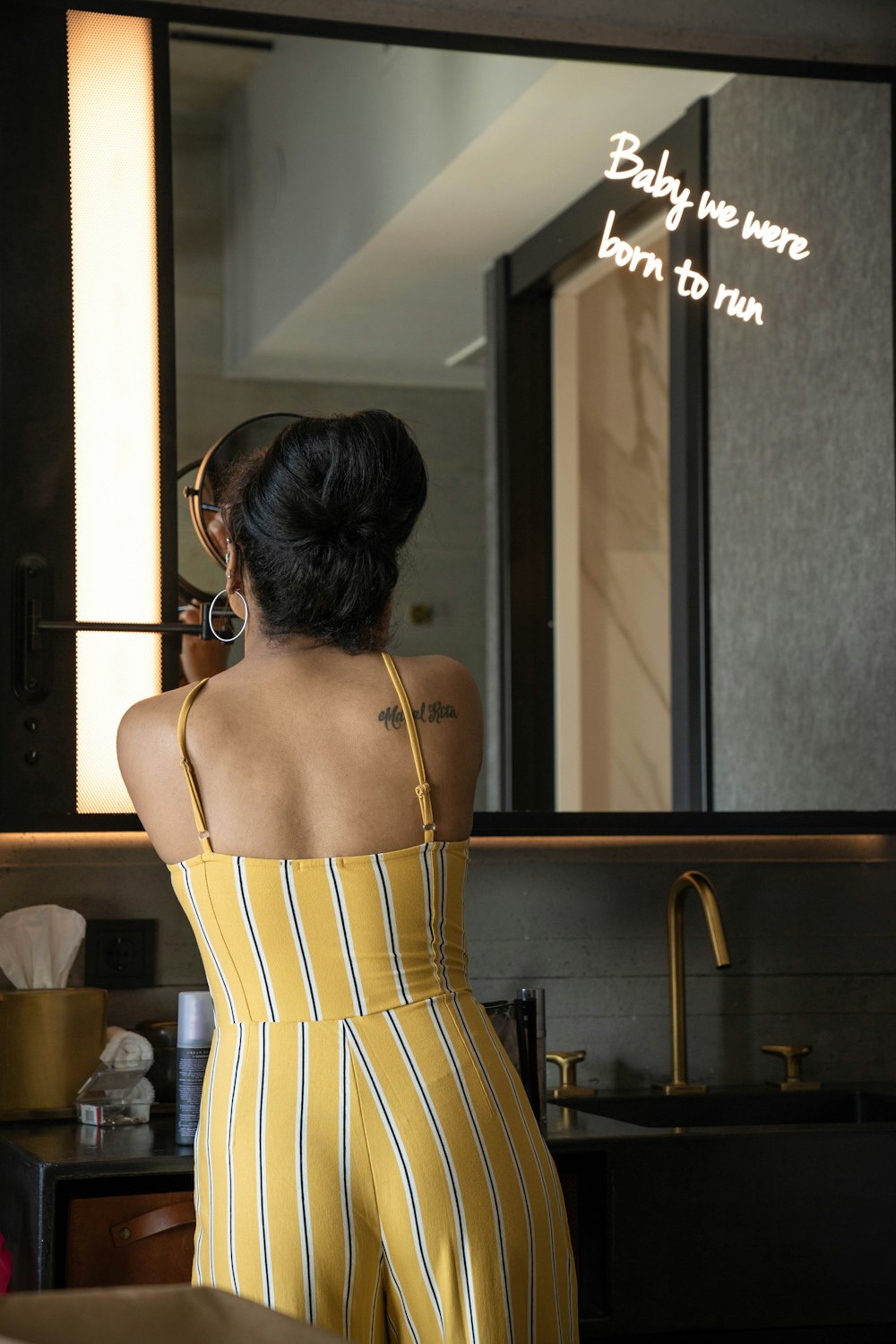 donna che indossa tuta gialla con spalline sottili vicino allo specchio