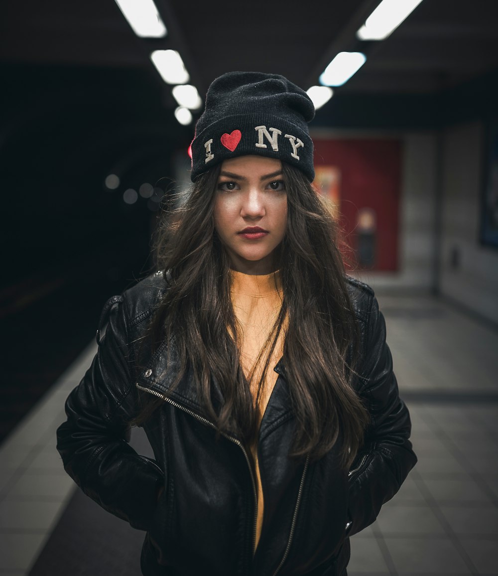 Femme debout portant une veste et une casquette en cuir noir