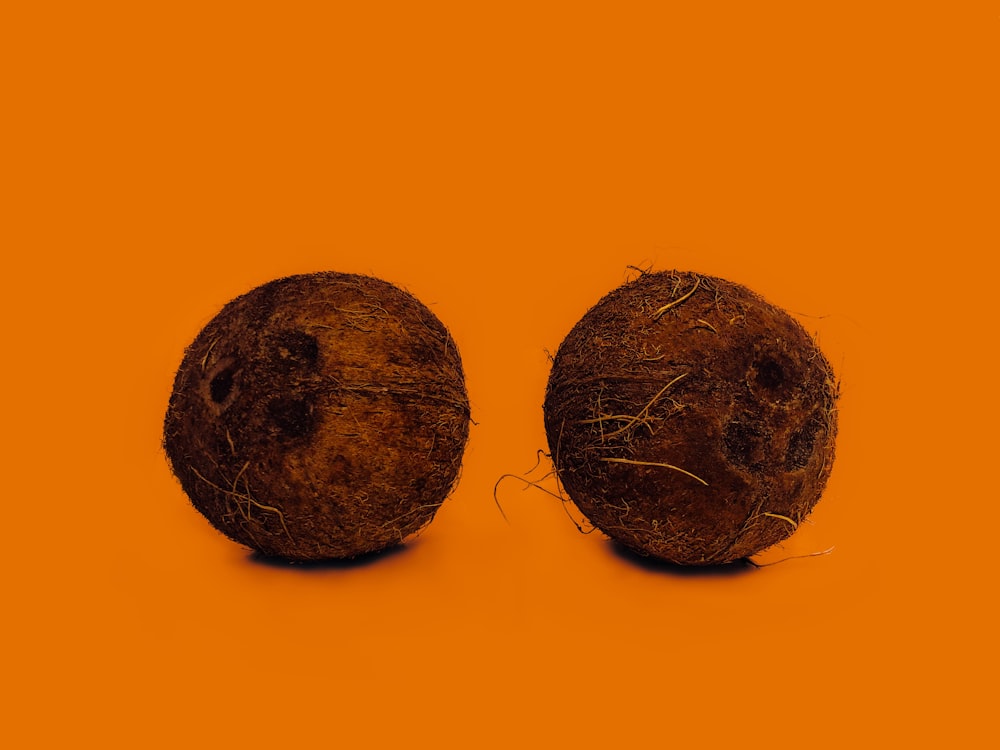 dos cáscaras de coco sobre superficie naranja