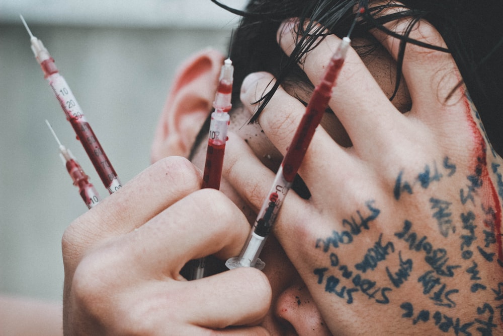 man holding syringes of red stain