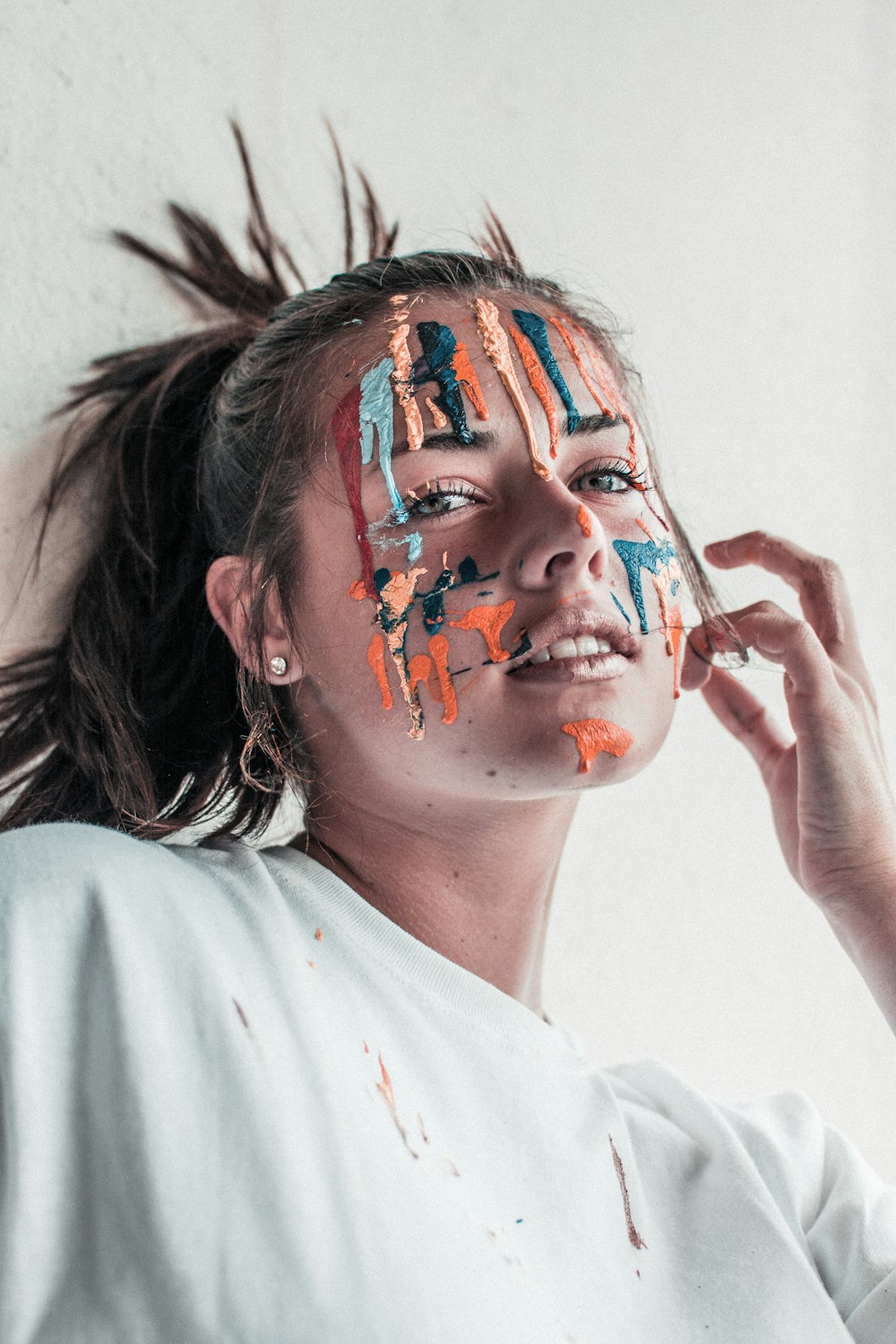woman leaning on wall with paint on face