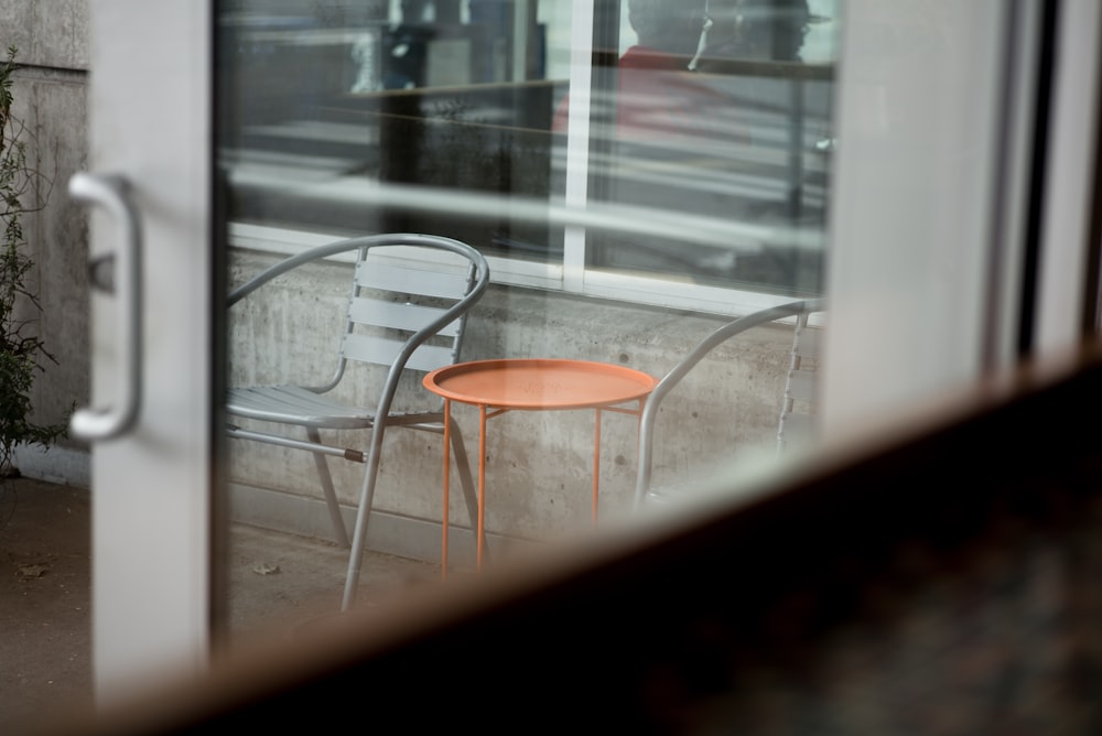 round orange metal table beside gray metal chair